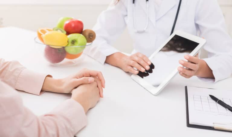 Nutritionist hands on the Tablet and Fruit Bowl next to Her — MedSurg Weight Loss in Brisbane, QLD